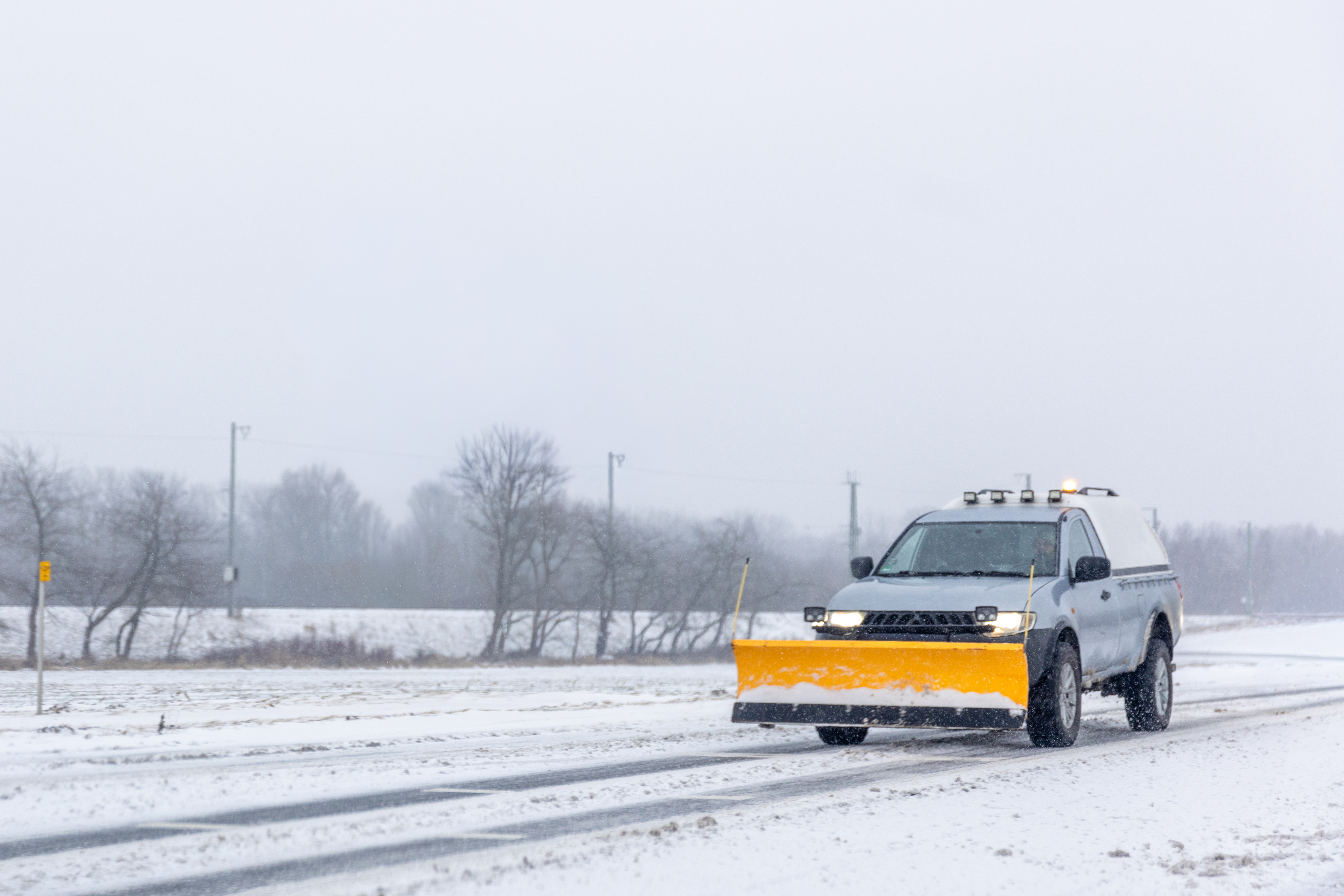 Snow plow truck clearing a road during winter storm